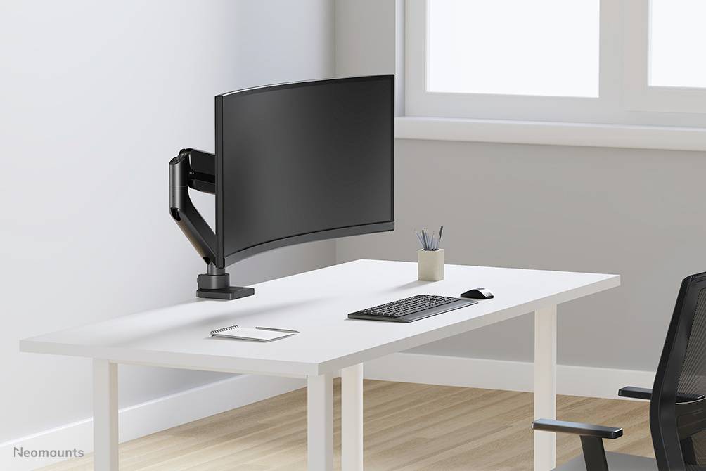 Egy modern, minimalista íróasztal íves monitorral egy állítható karon, billentyűzettel, tolltartóval és irodai székkel.