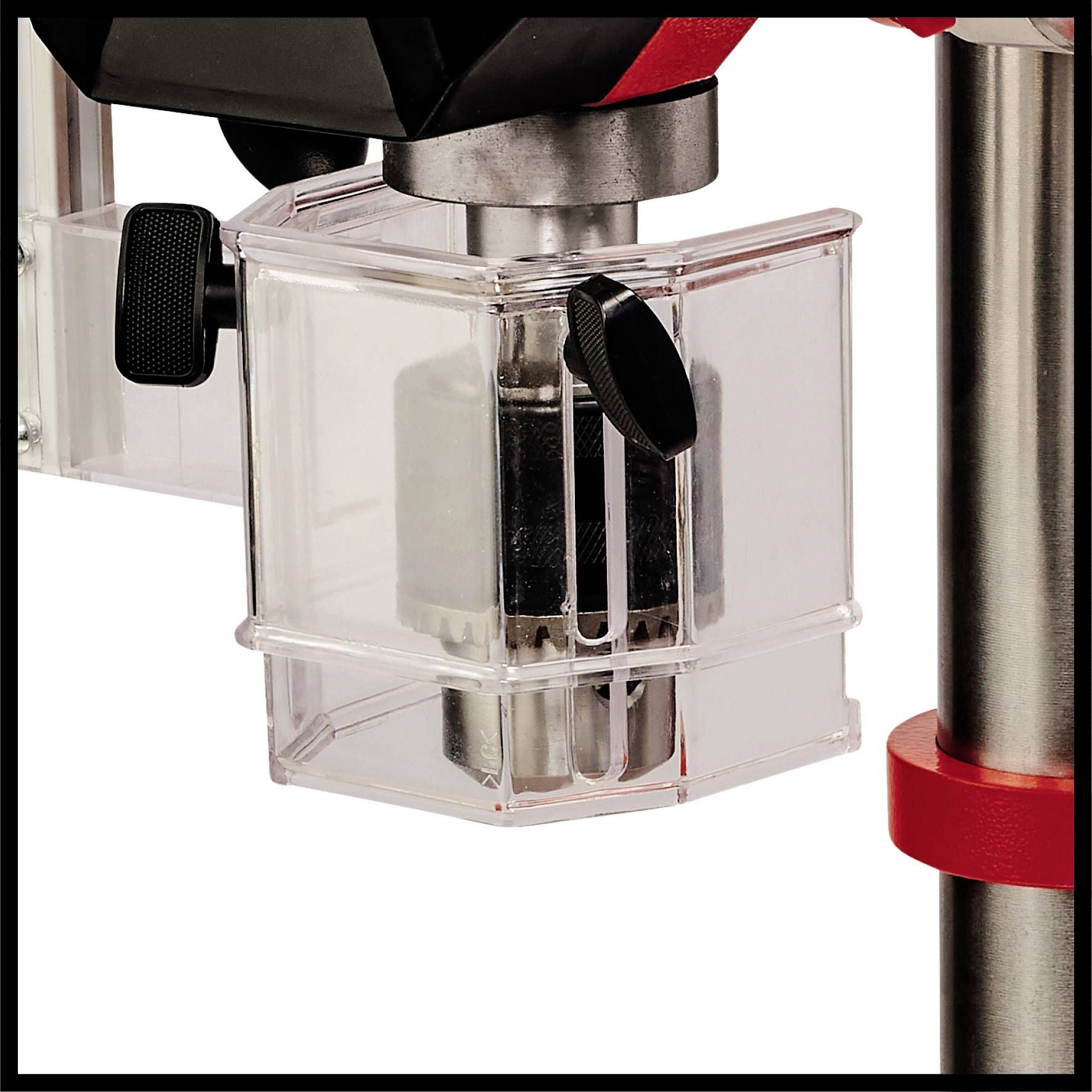 Egy átlátszó védőburkolat veszi körül egy piros-ezüst fúrógép fúrófejét. A védőburkolat egy fogantyú segítségével nyitható vagy állítható.