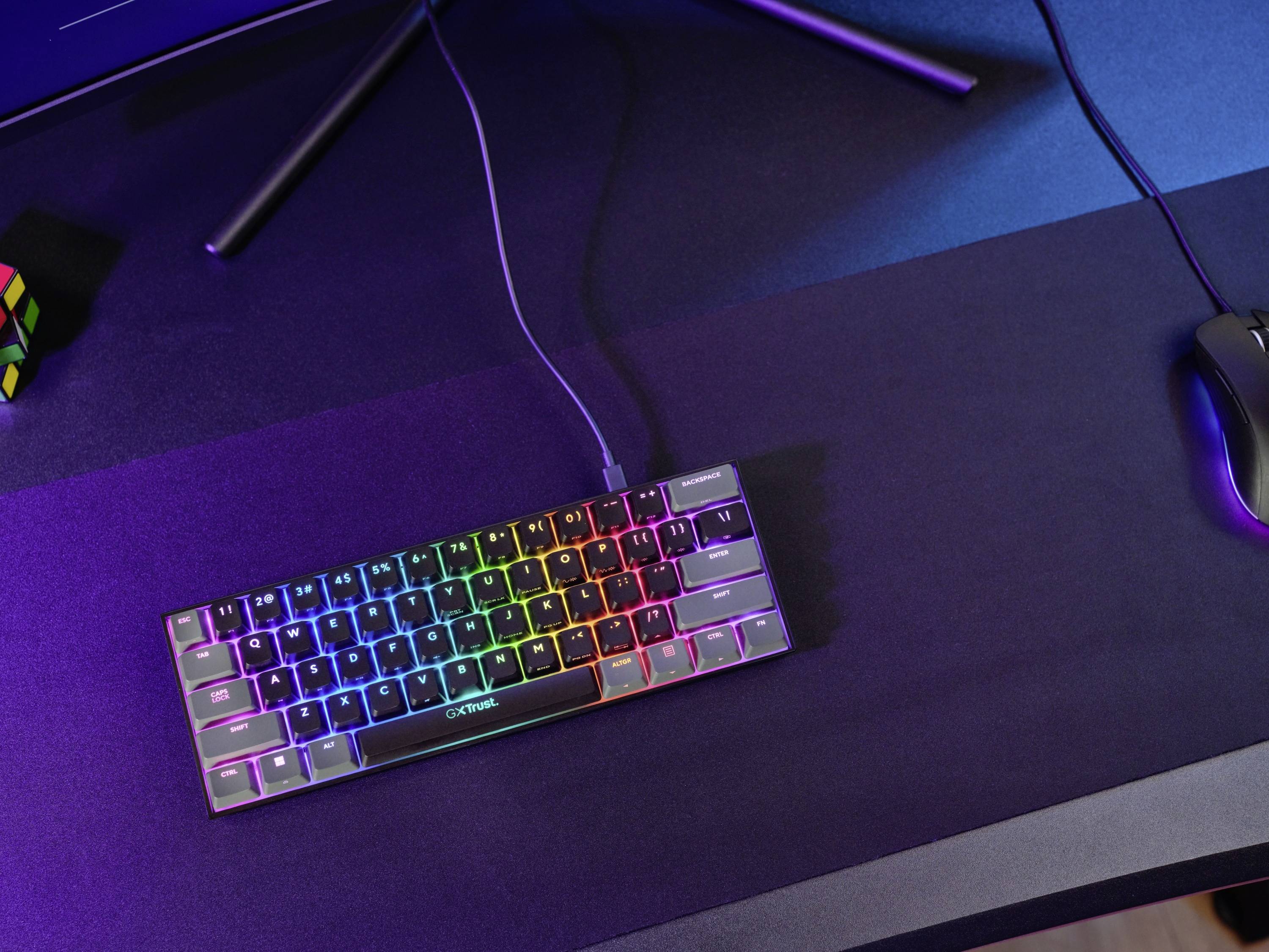 Mechanikus billentyűzet RGB-háttérvilágítással egy íróasztalon, mellette egy számítógépes egér és egy Rubik-kocka.