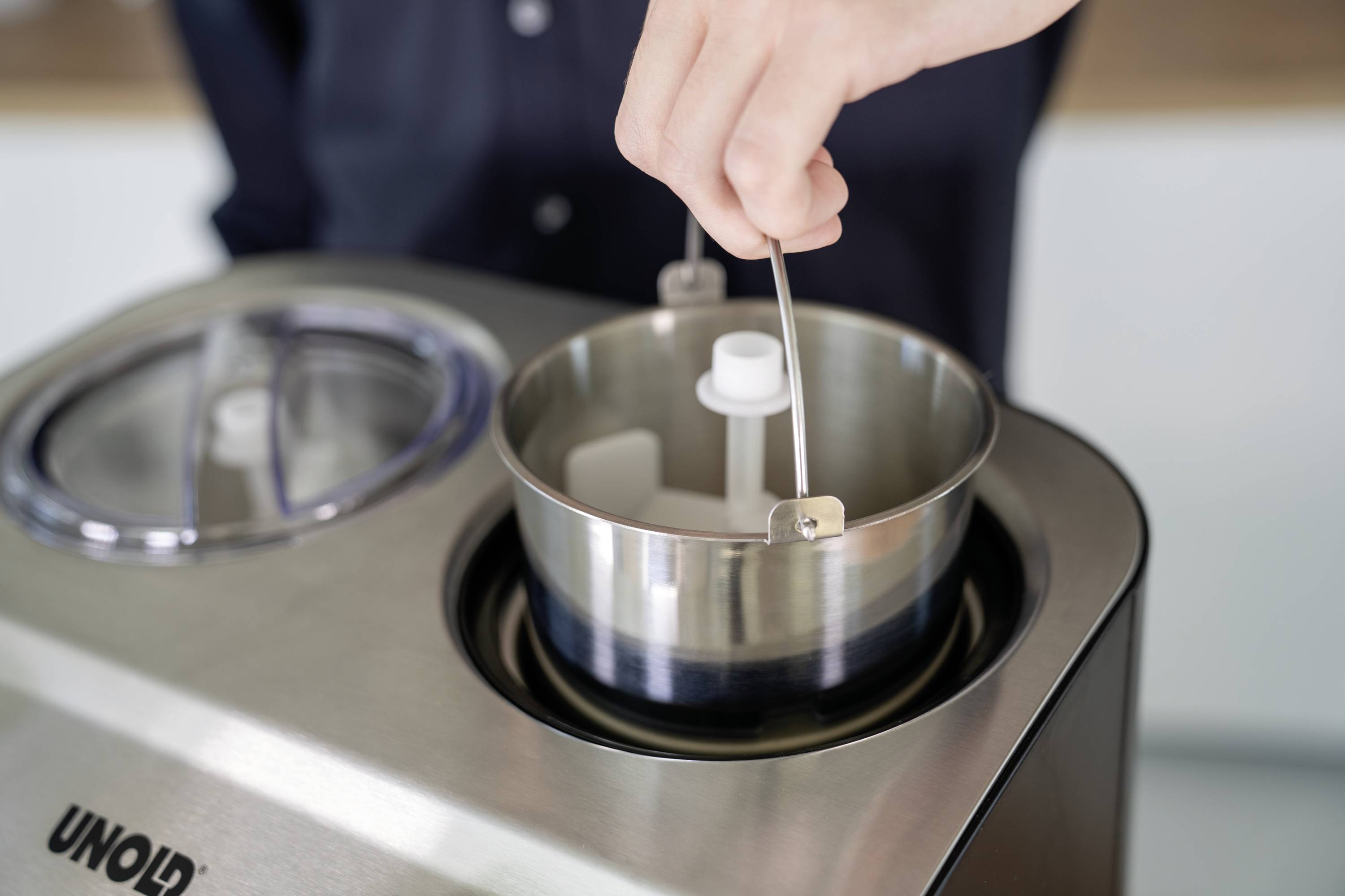 Egy személy kiveszi a keverőlapátot egy fagylaltgépből, hogy kivegye a kész fagylaltot.