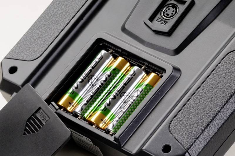 Egy elektronikus eszköz kinyitott elemtartója, amelybe négy darab AA-típusú elem van behelyezve.