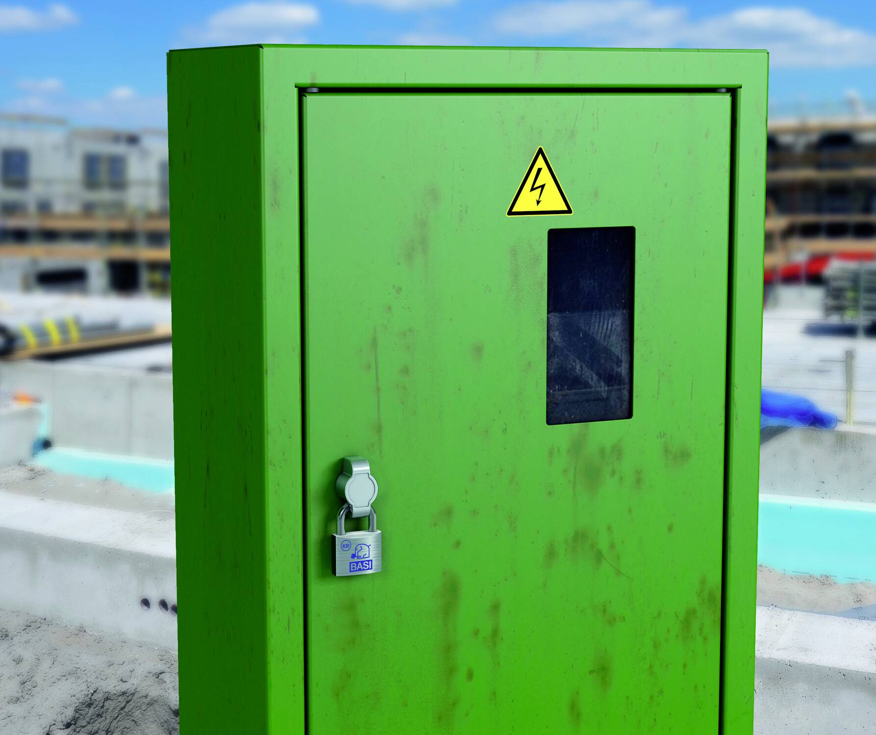 Zöld elektromos elosztószekrény villamos veszélyre figyelmeztető szimbólummal. Zár a ajtaján. Építkezési terület a háttérben.