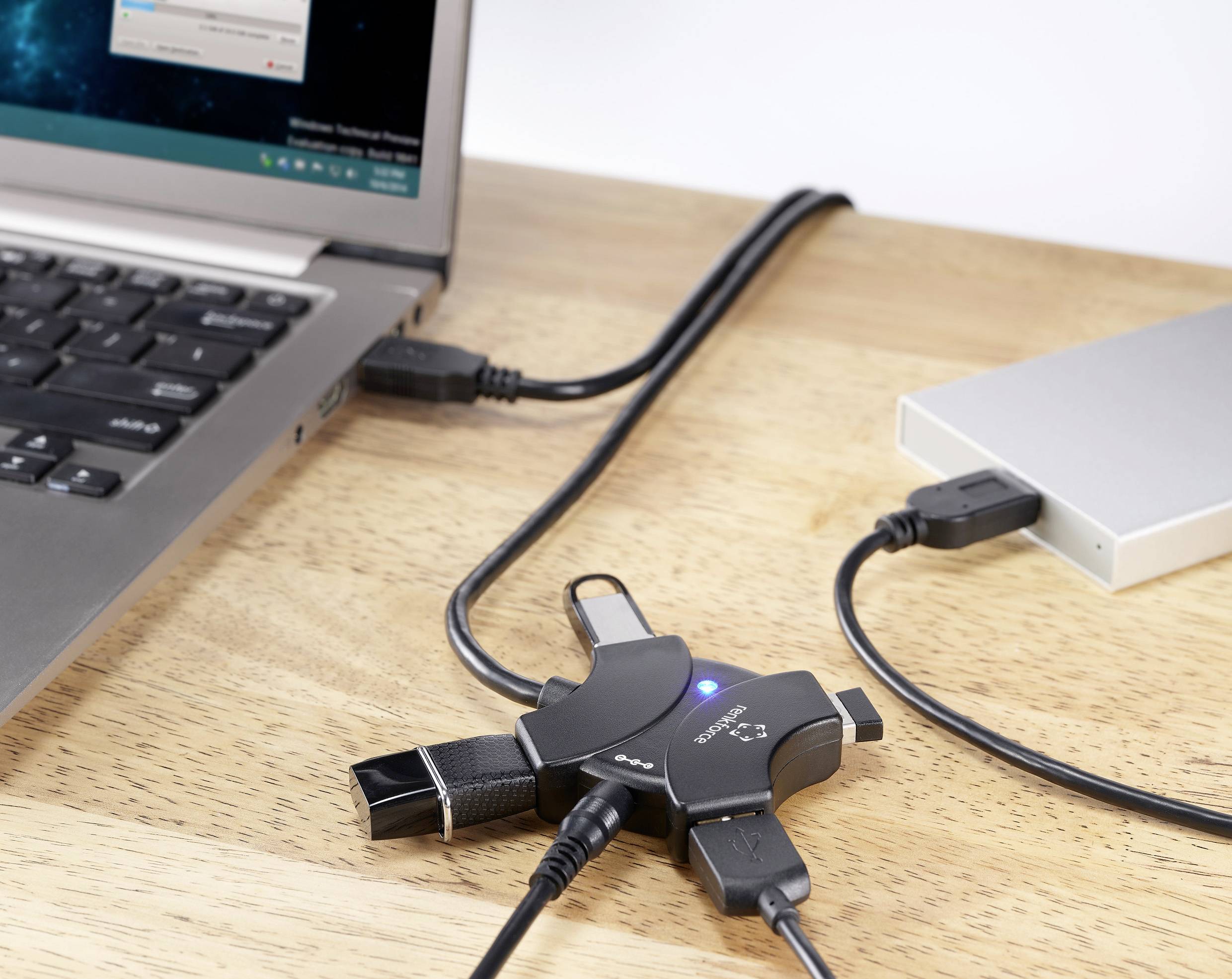 USB-elosztó négy eszközzel: laptop, külső merevlemez, USB-pendrive és kábel. Bemutatja az elosztó csatlakozási képességét és funkcionalitását.