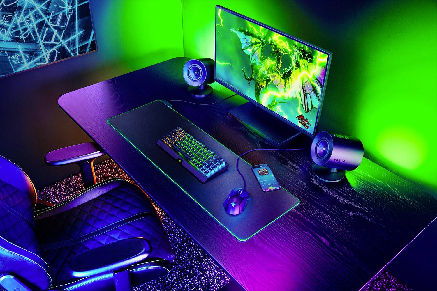 Számítógép-beállítás zöld és kék LED-világítással, billentyűzettel, egérrel és monitorral egy íróasztalon. A háttérben grafika látható a monitoron.