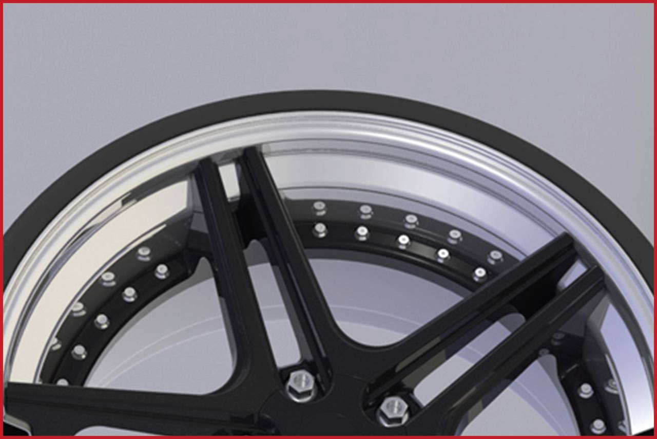 Egy fekete autókerék-felni közelképe fényezett részletekkel és csavarokkal a szélén.