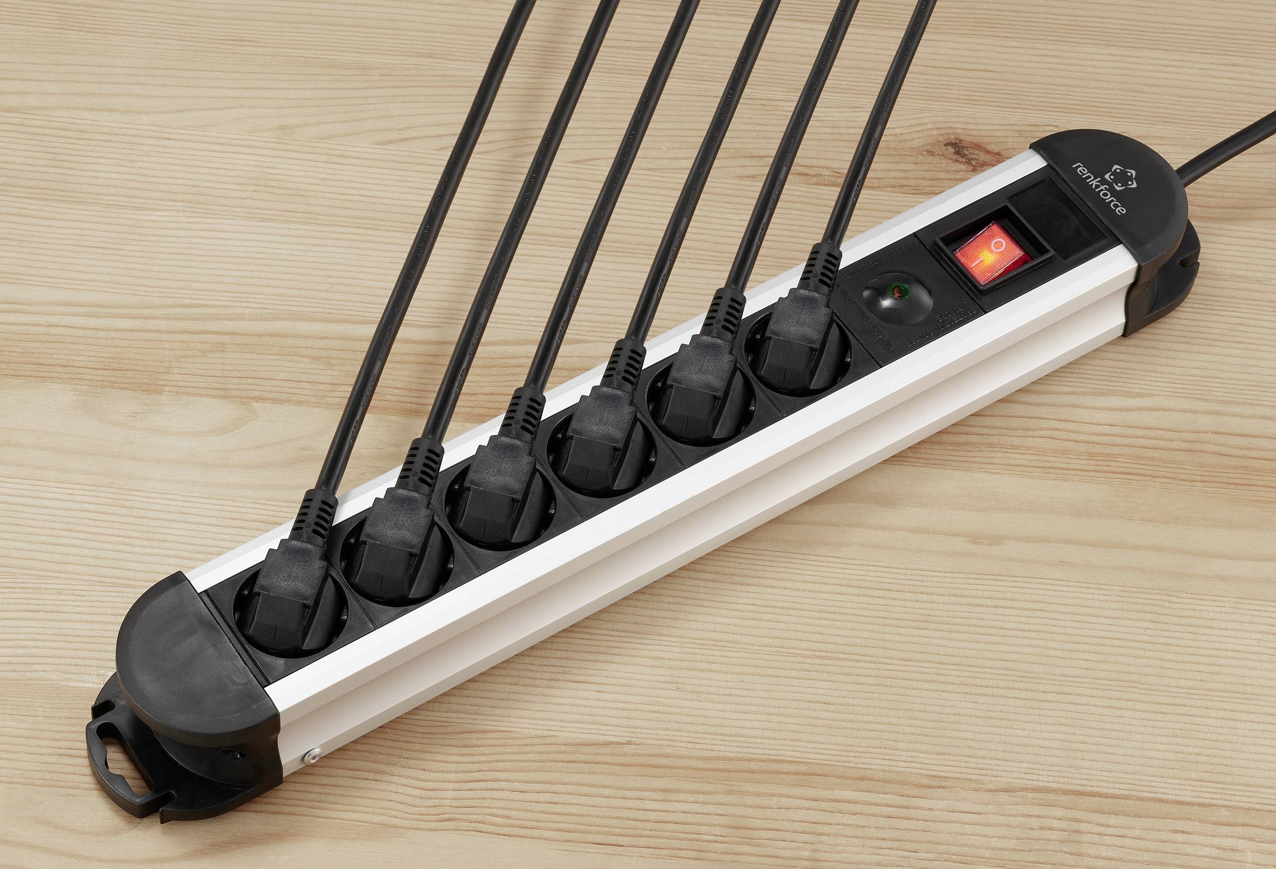 Egy hatágú elosztó hat bedugott hálózati kábellel egy fa asztalon; a bekapcsoló gomb piros.