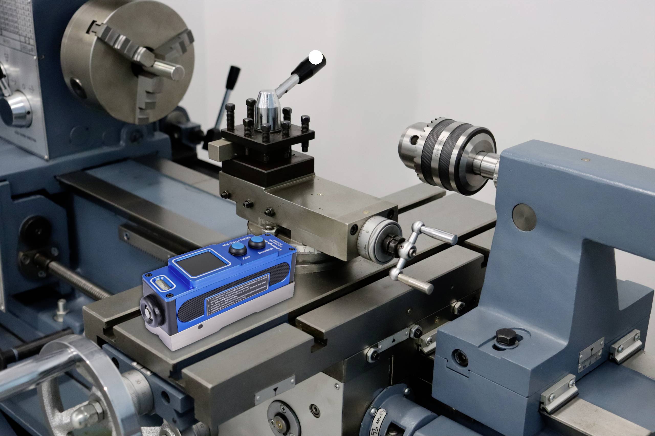 Egy kék rádió egy ipari környezetben egy fém esztergagép ágyon helyezkedik el.