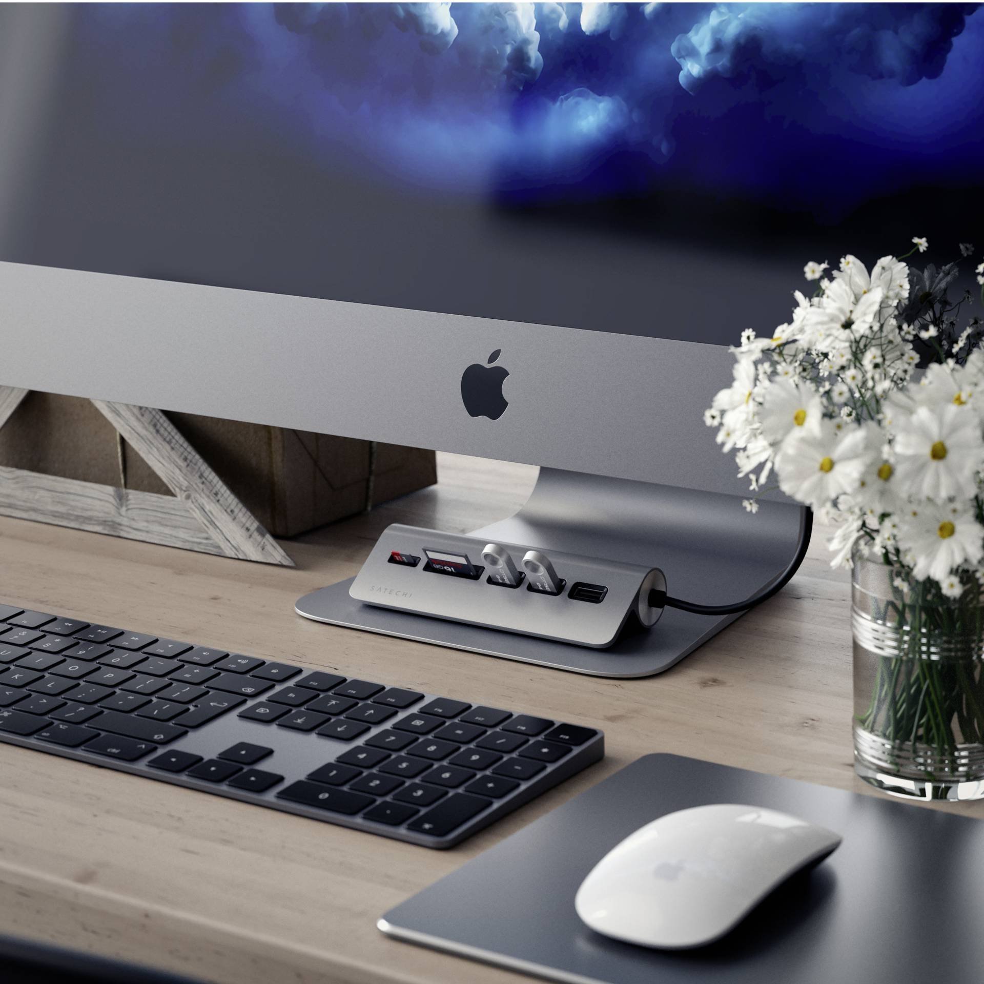 Egy íróasztal egy számítógéppel, billentyűzettel és egérrel. Mellette egy váza virágcsokorral.