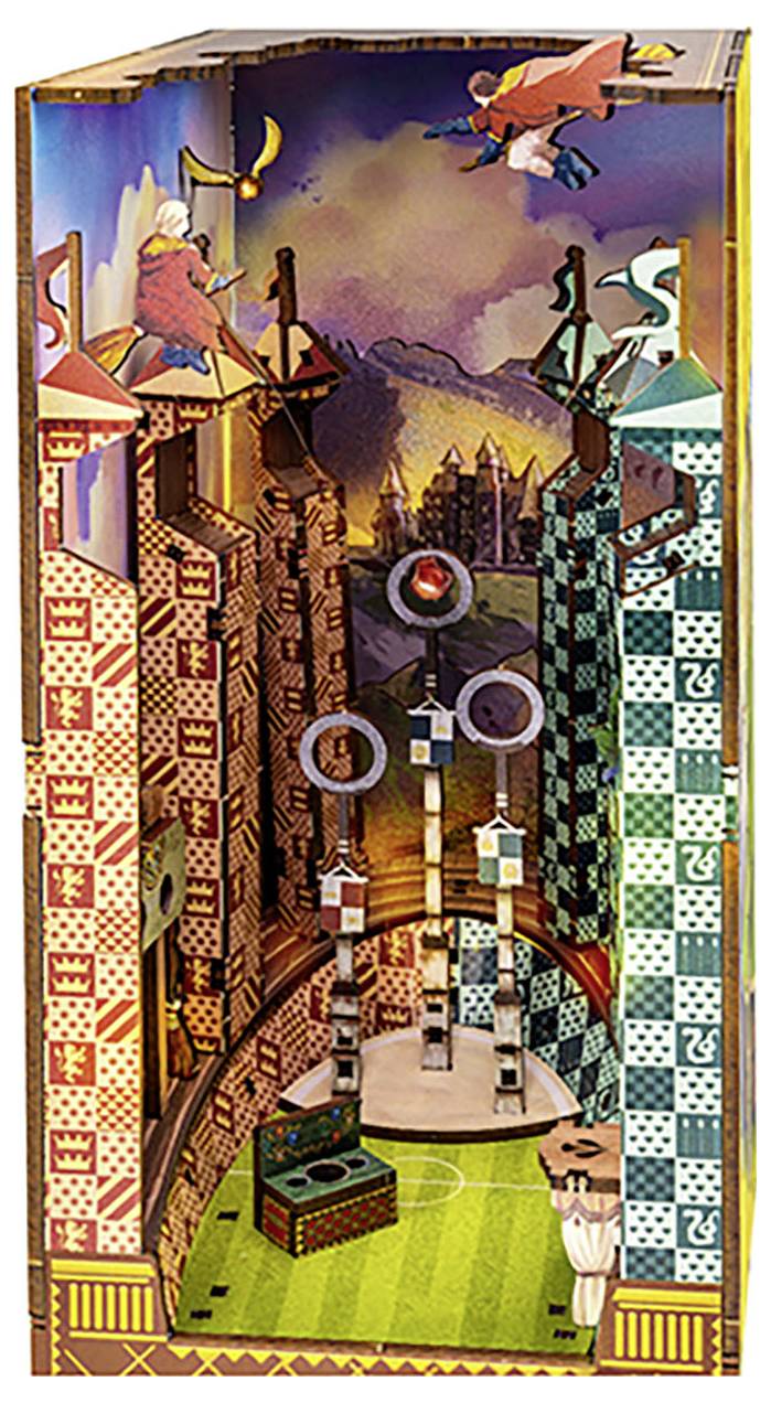 Egy háromdimenziós dioráma mutat egy Quidditch-jelenetet két csapattal egy színes stadionban. Boszorkányok és varázslók seprűkön repkednek a tornyok felett.