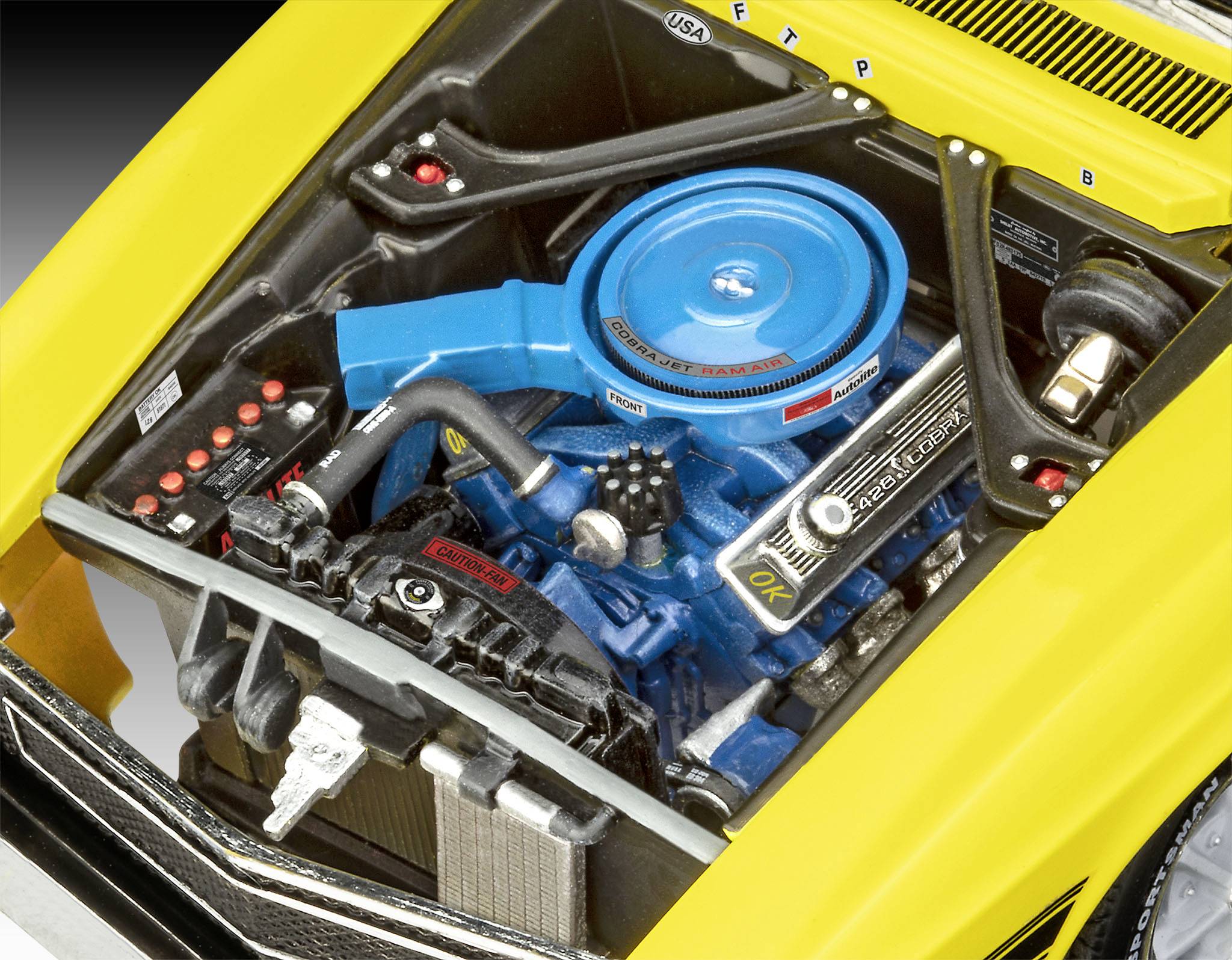 A sárga sportautó motorterét mutatja, ahol egy kék V8-as motor fekete tömlőkkel és kábelekkel középen helyezkedik el.