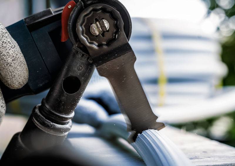 Közelkép egy kábelvágóról, amint éppen elvág egy kábelt. Egy kéz tartja az ollót, a háttérben további kábelek láthatók.