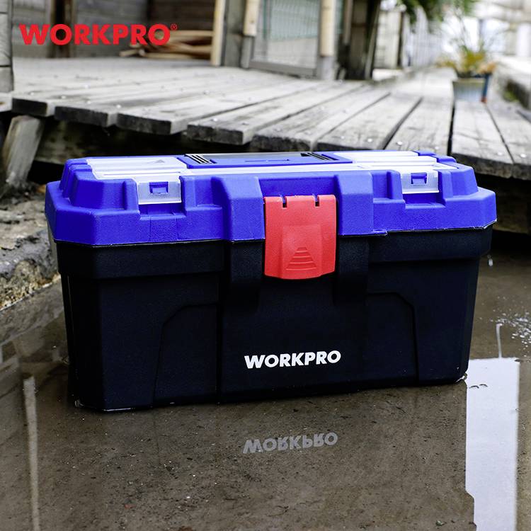 Kék és fekete szerszámosláda piros csattal, egy nedves járdán elhelyezve. A ládán felirat: 'WORKPRO'. Épülethomlokzat a háttérben.