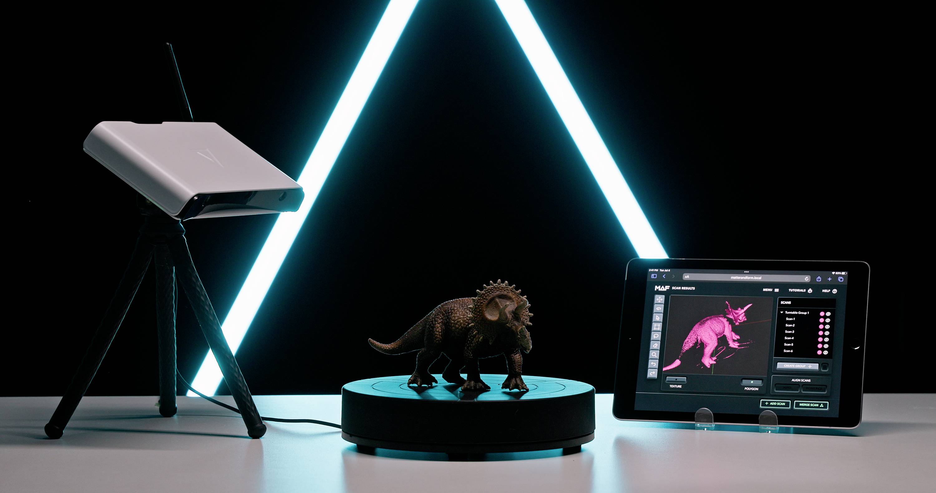 Egy 3D-szkenner letapogatja a dinoszaurusz modellt, miközben egy táblagép mutatja a 3D-renderelés eredményeit. A háttérben LED-szalagok világítanak.