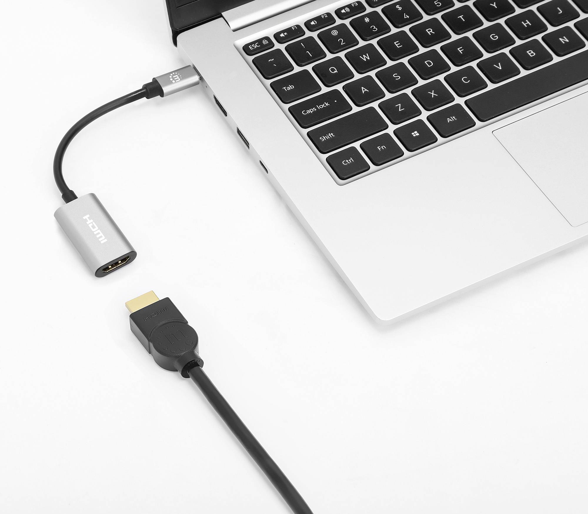 Egy laptop HDMI-csatlakozóval, amelyhez egy adapter van csatlakoztatva egy HDMI-kábelen keresztül.