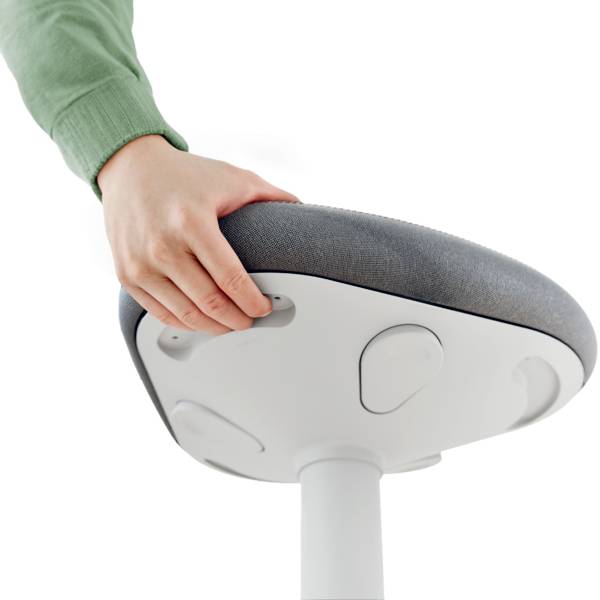 Egy személy egy modern, ergonomikus szék ülésfeletét tartja, amelynek szürke kárpitja van és fehér talapzaton áll.