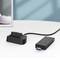 Egy strukturált házú USB-adapter fehér felületen fekszik, egy kisméretű fekete dokkolóállomáshoz csatlakoztatva.