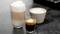 Három különböző kávétípus: egy pohár latte macchiato, egy csésze cappuccino és egy espresso egy kis pohárban sötét asztalon.