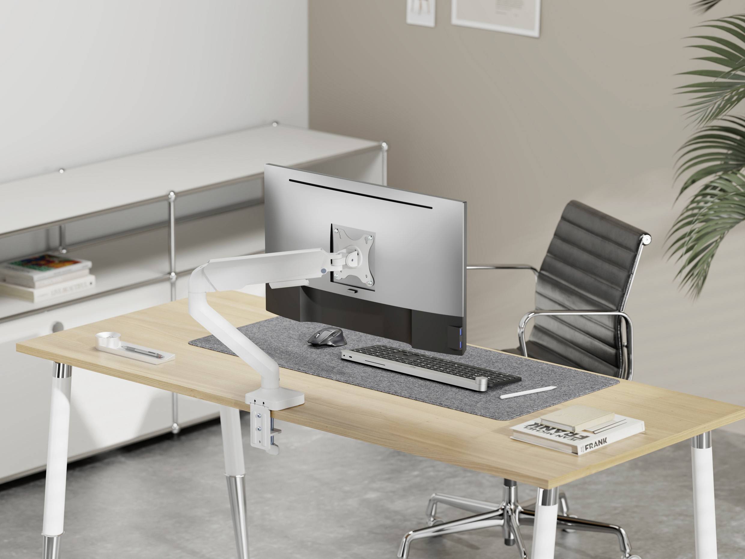 Egy modern íróasztal egy ergonomikus székkel, monitorral mozgatható karon, billentyűzettel, egérrel és egy füzettel.