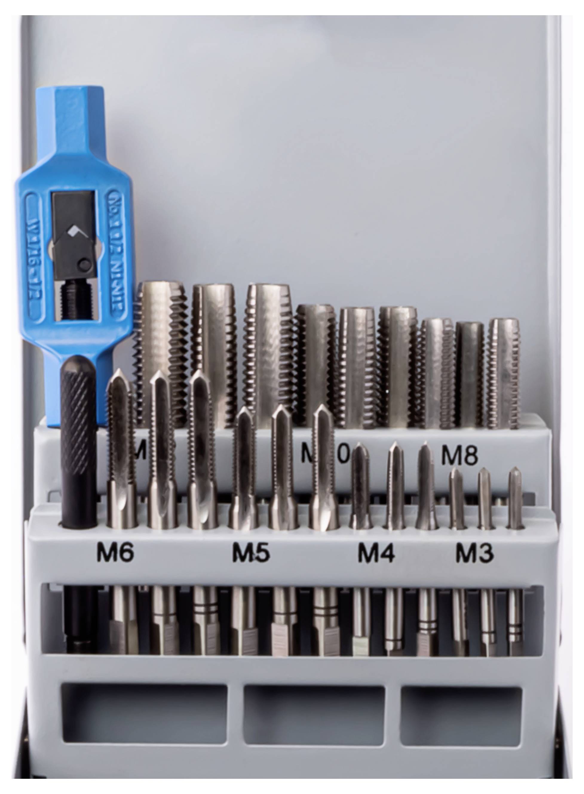 Egy fémfúrók készlete különböző méretekben, M3-tól M8-ig, egy tartóban rendezve. Egy kék szerszám van elhelyezve bal felül.