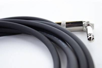 Egy fekete audiókábel derékszögű fémcsatlakozóval, feltekerve és használatra készen audio- vagy zenei alkalmazásokhoz.