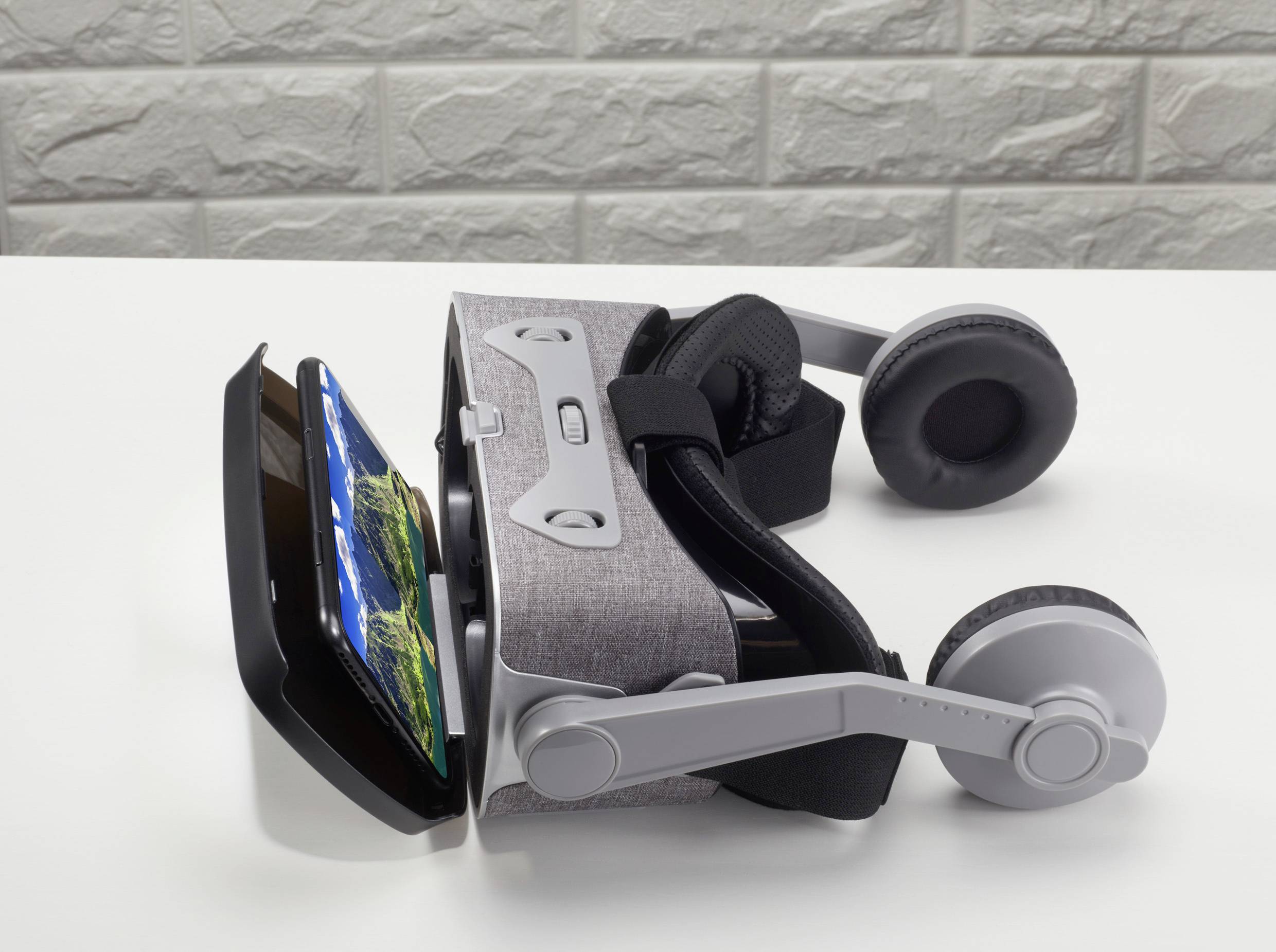 Egy VR-headset fekszik egy asztalon. Egy okostelefon van bedugva a headsetbe, és egy tájképet jelenít meg a kijelzőn.