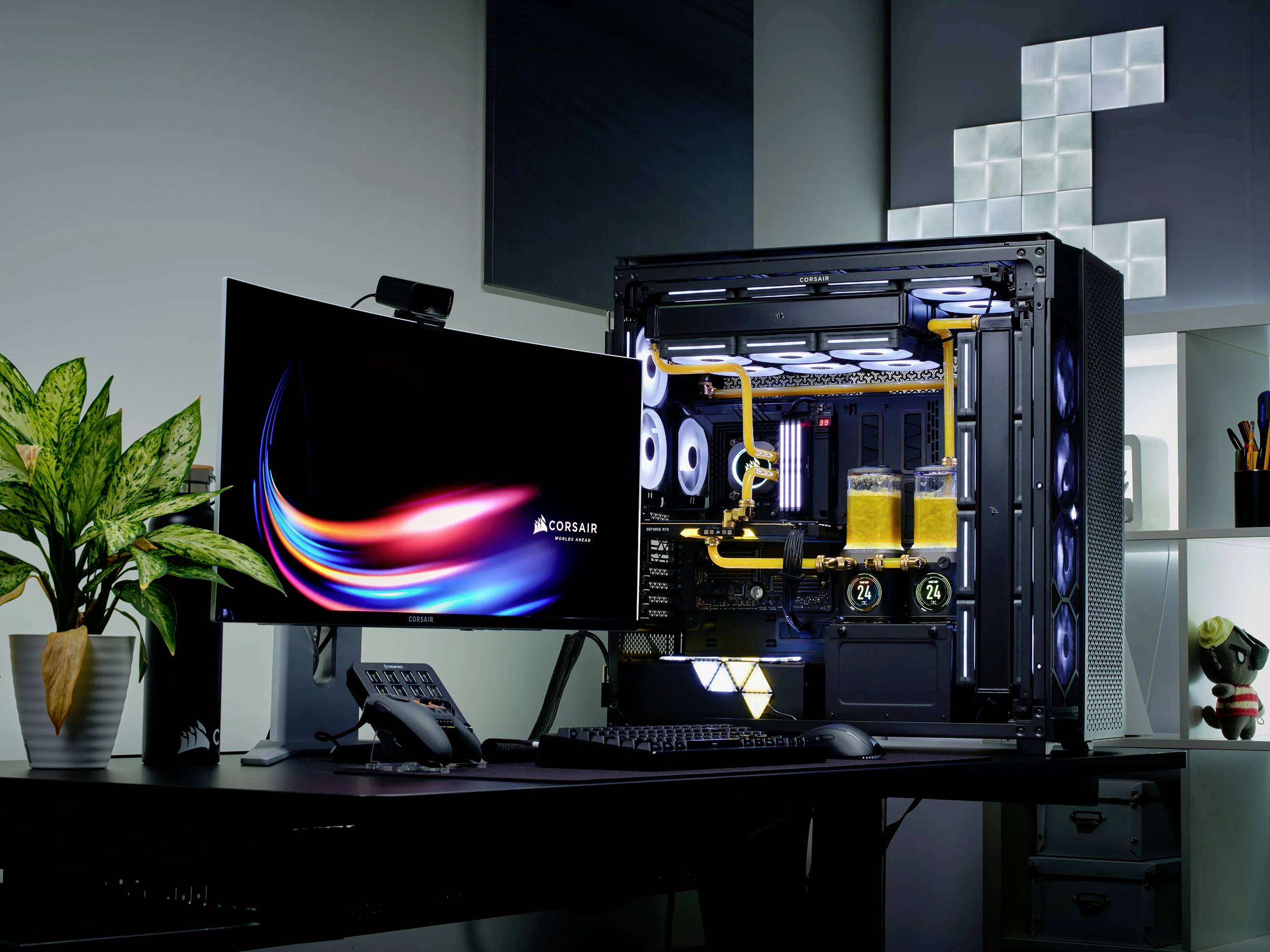 Egy modern számítógépes munkahely megvilágított gaming PC-vel, nagy monitorral, billentyűzettel és növénnyel fekete asztalon.