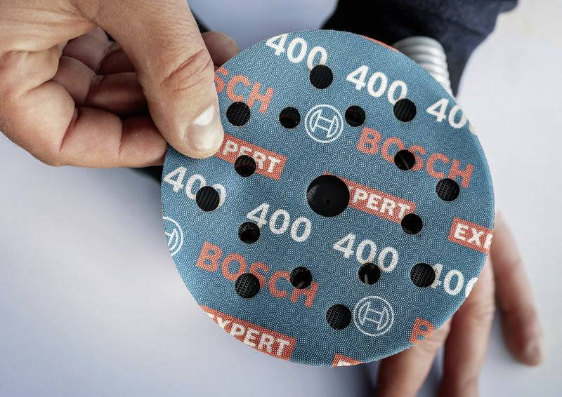 Egy kéz által tartott csiszolópapír 'BOSCH EXPERT' felirattal és '400'-as szemcsemérettel. Elektromos csiszológépekhez alkalmas.