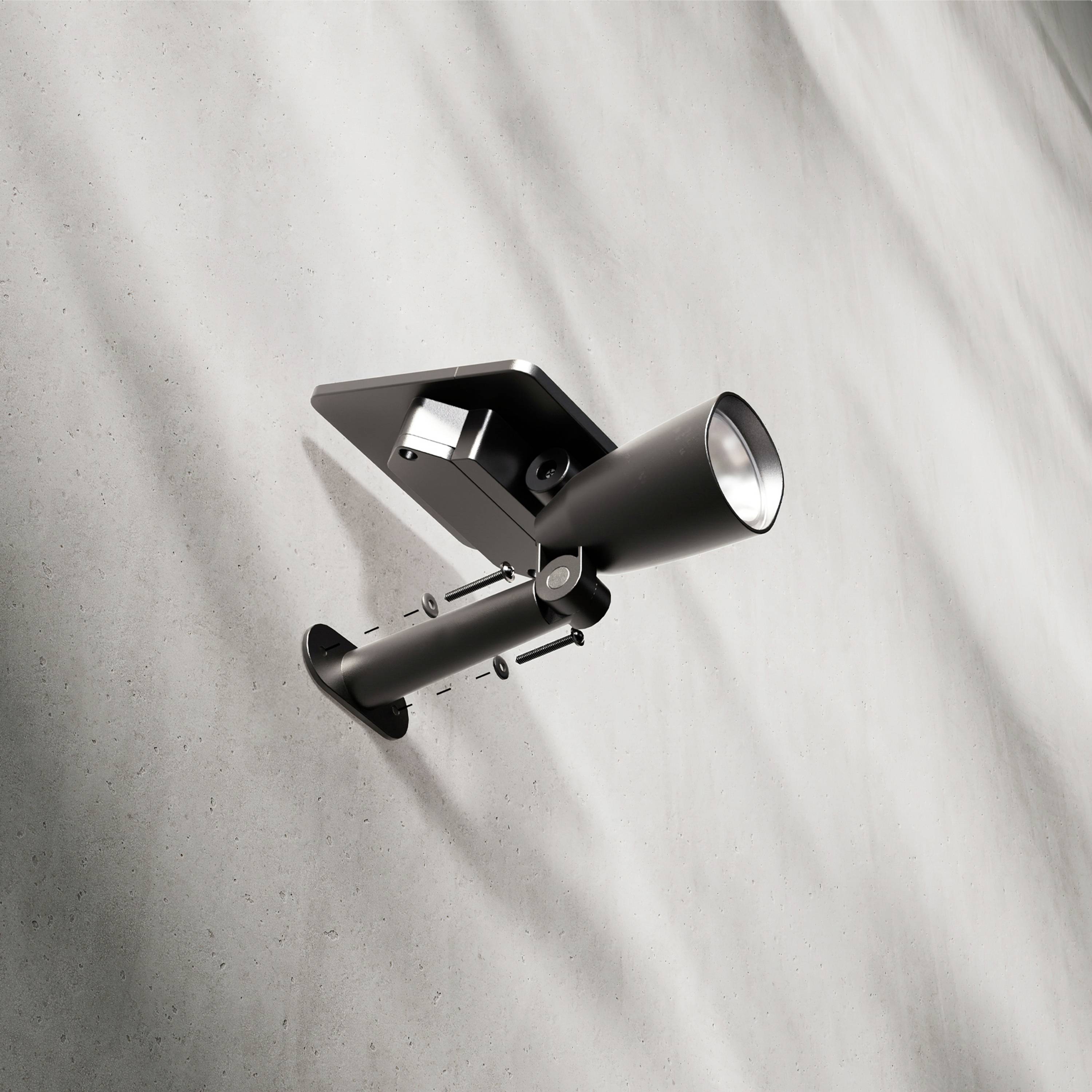 Modern, fekete fali lámpa, falra szerelve. Kúpos formájú ernyője lefelé irányul.