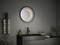 Egy fürdőszoba sötét mosdókagylóval, stilizált csapteleppel, kerek tükörrel, amely egy világító félhold dizájnt mutat, és törölközőkkel.