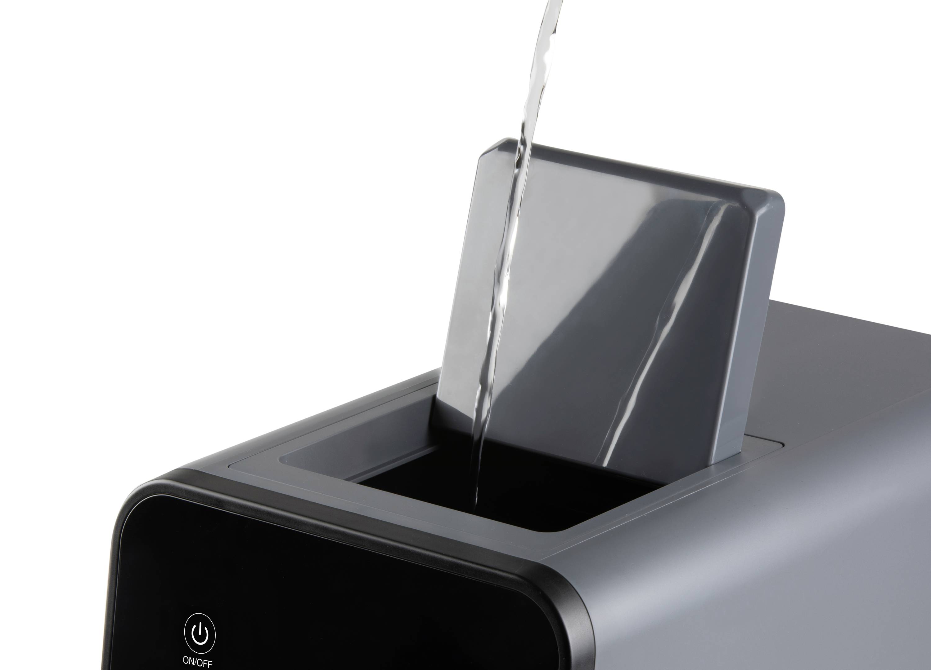 Egy vízsugarat öntenek egy szürke levegőpárásító betöltőnyílásába. A levegőpárásító be van kapcsolva.