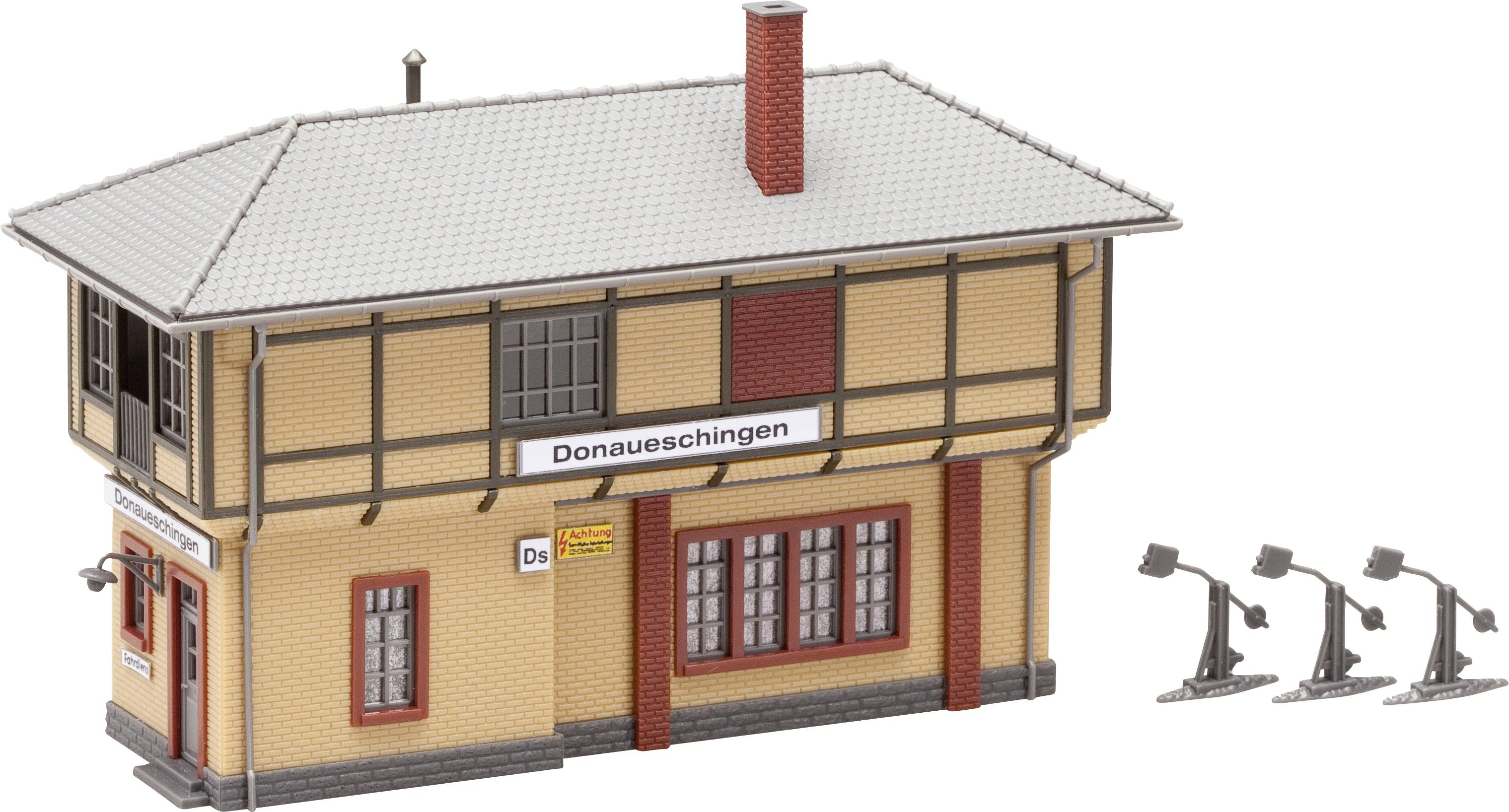 Egy vasútállomás épületének makettje, amelyen 'Donaueschingen' felirat látható, világosbarna falakkal, vörös cseréptetővel és négy lámpa van az oldalán.