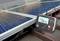 Egy digitális multiméter, amelyen '25.7V' látható, csatlakoztatva van egy napelemhez. A beállítás a fotovoltaikus rendszerek feszültségmérését szemlélteti.