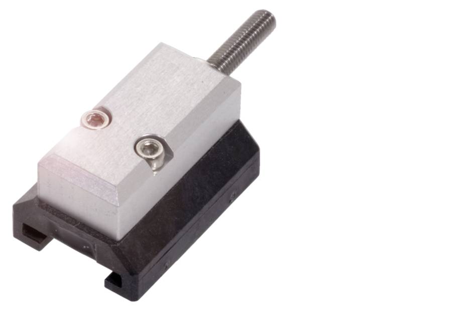 Fémkomponens csavarral fekete tartón, valószínűleg egy mechanikai vagy elektronikai berendezés része.