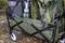 Egy kempingfelszereléssel megrakott kocsi, amely hátizsákokat, egy lámpást és zsákokat tartalmaz, leveles talajon a szabadban.