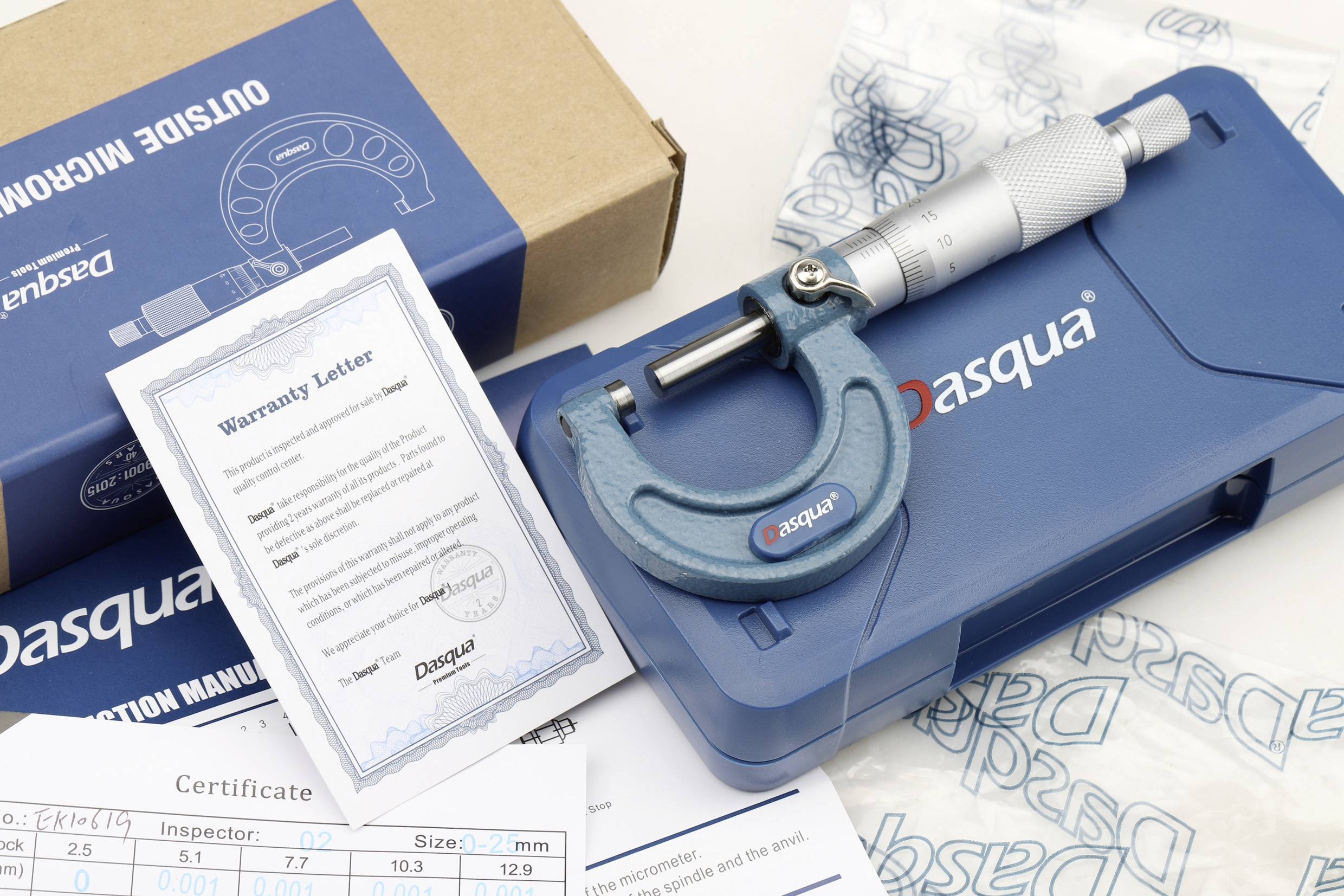Kék mikrométer, garancilevél és tanúsítványok egy asztalon, Dasqua márkás csomagolással.