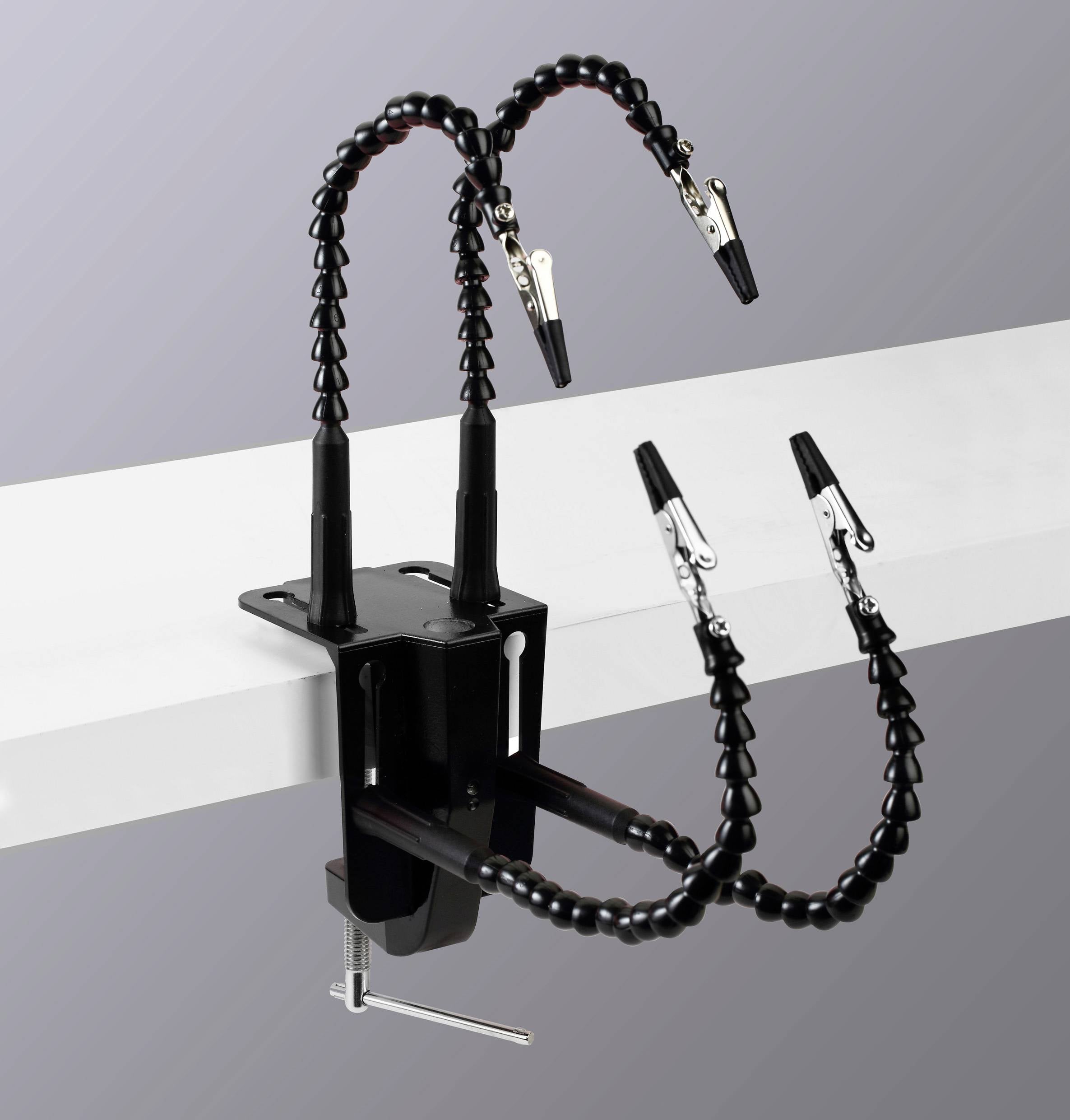 Egy rugalmas bilincs, amely négy krokodilcsipeszt tart állítható karokon, egy sík felülethez rögzítve, használható tárgyak rögzítésére szerelés vagy javítás során.