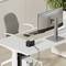 Egy modern, minimalista home office, nagy monitorral egy fehér íróasztalon, egy székkel és egy cserepes növénnyel a sarokban.