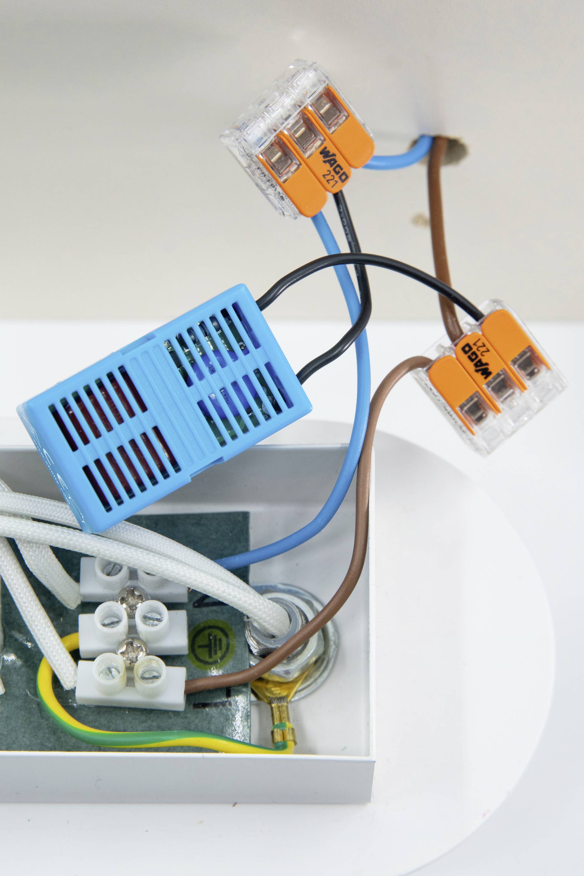 Elektromos dobozban egy kék egyenáramú érzékelő narancssárga WAGO csatlakozókkal történő bekötésének ábrázolása, amely egy egyszerű elektromos elrendezést mutat be.