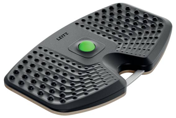 Egy fekete, ergonomikus lábtámasz, textúrált felülettel és központi zöld gombbal, amelyet az íróasztalnál történő ülés közbeni kényelem és testtartás javítása érdekében terveztek.
