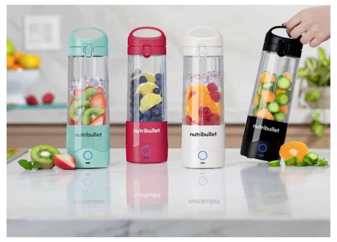 Négy hordozható turmixgép – türkizkék, piros, fehér és fekete színben – gyümölcsökkel megrakva áll a pulton. Egy kéz a fekete turmixgép felé nyúl.