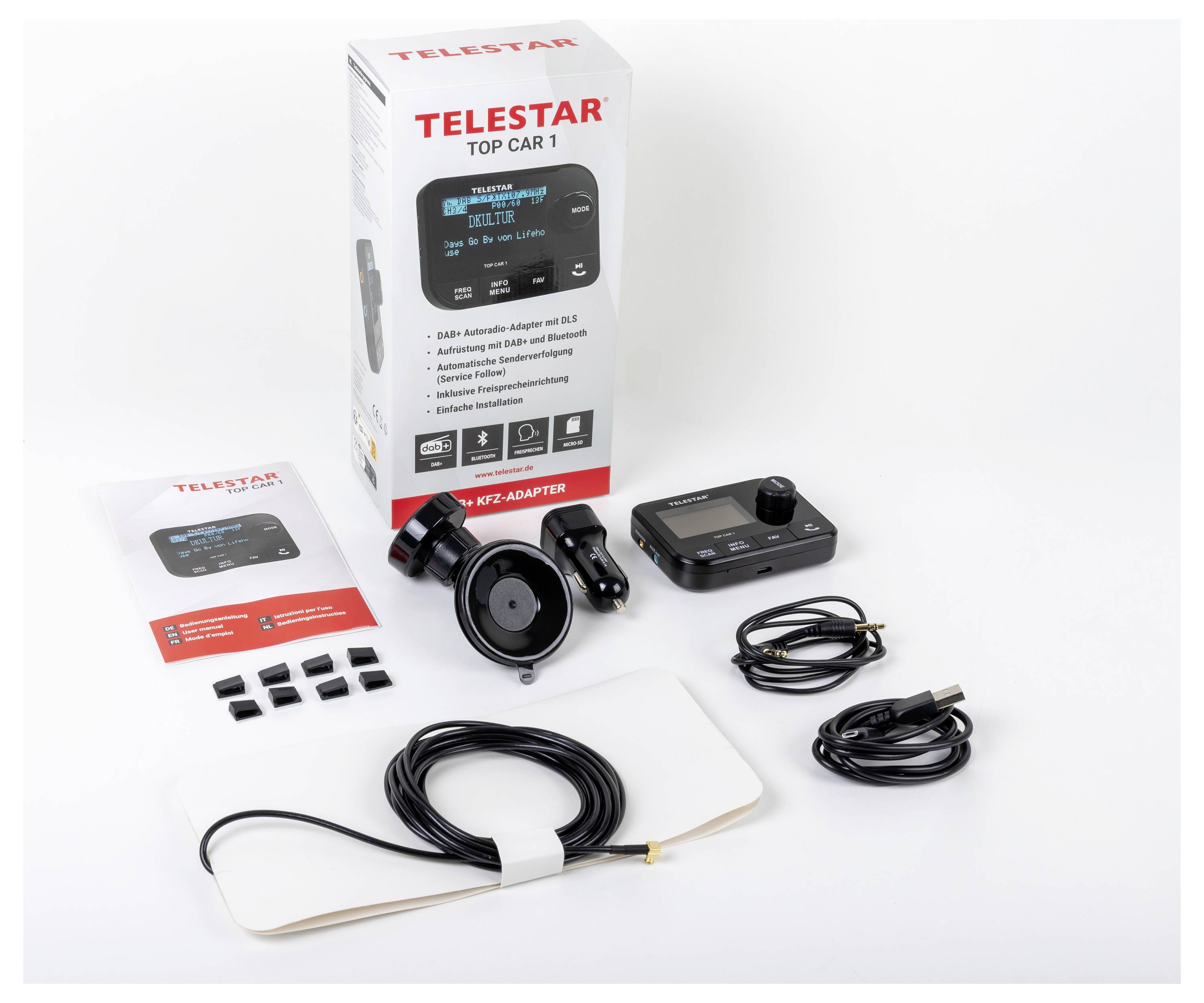 A 'Telestar Top Car 1' készlet főegységgel, kábelekkel, adapterekkel, kézikönyvvel és csomagolódobozzal együtt kiállítva. Kiegészítők rendezetten elrendezve.