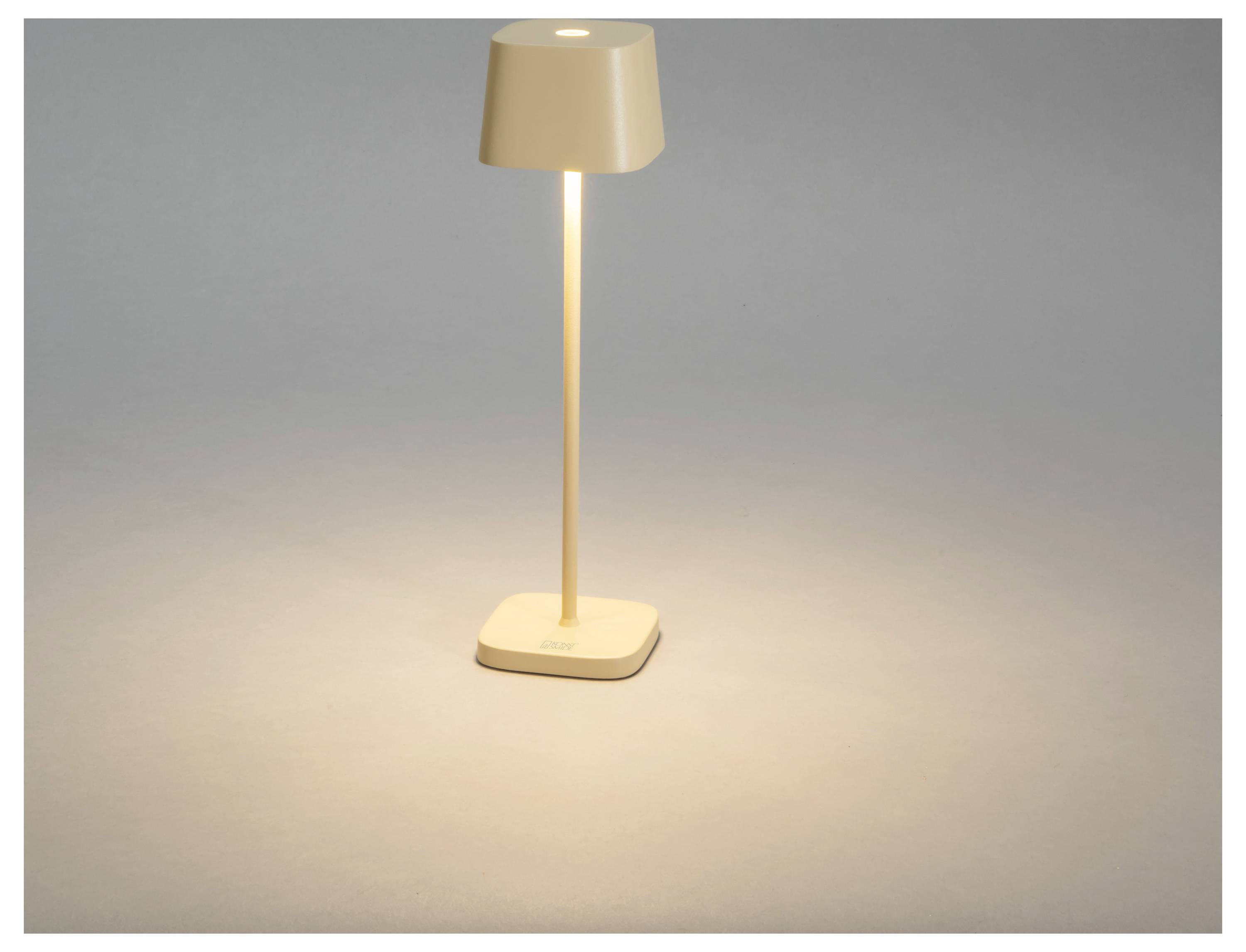 Egy karcsú, modern asztali lámpa, bézs színben, puha fényt áraszt egy szürke háttér előtt, kiemelve elegáns, minimalista formatervezését.