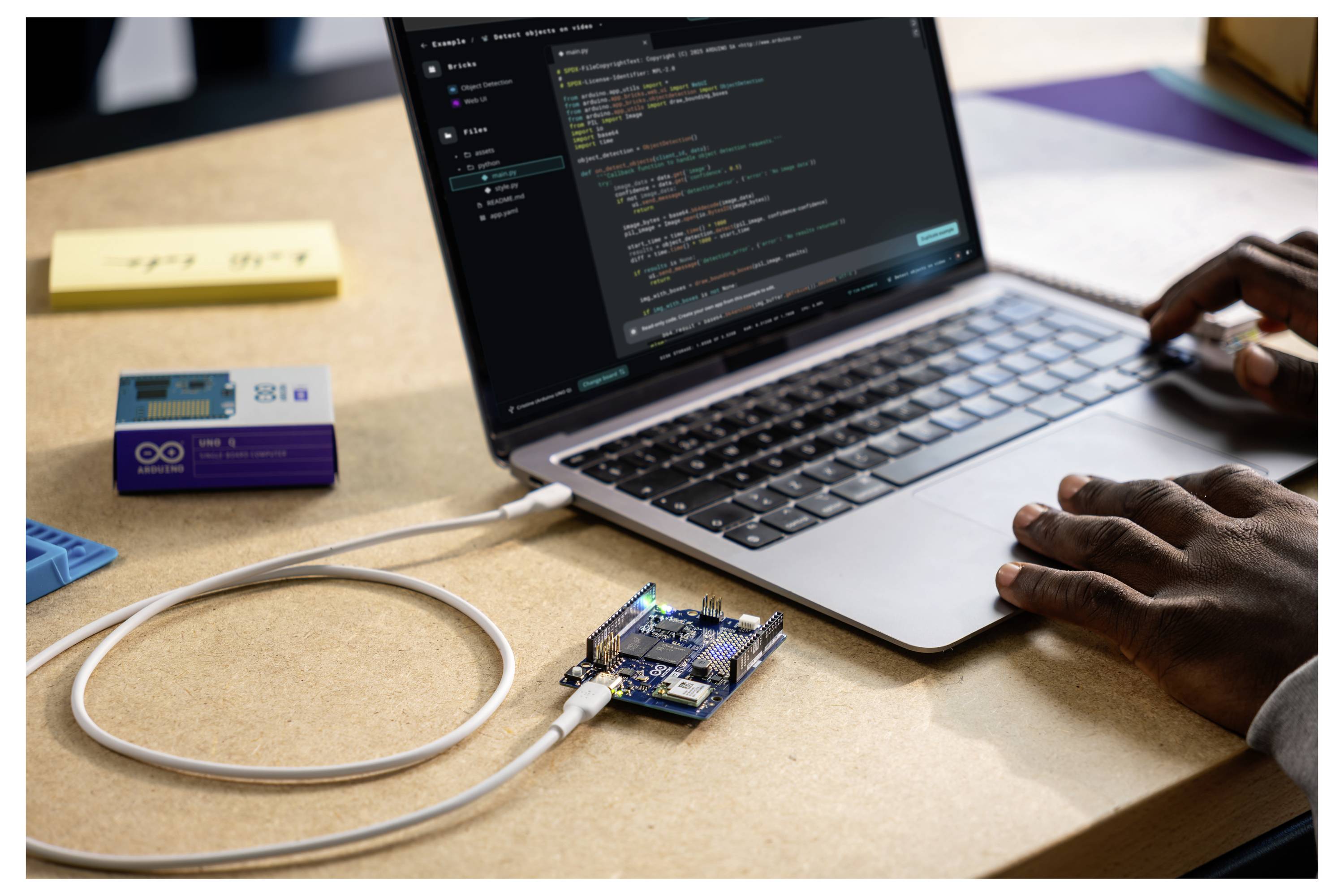 Egy személy egy laptopon gépel, amely egy Arduino alaplaphoz van csatlakoztatva, a képernyőn kód látható.