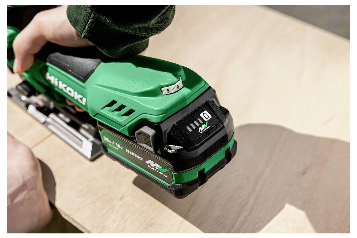 Egy személy egy zöld Hikoki kéziszerszámot használ egy fa felületen, precíziós munkát végezve. A szerszámon jól látható a márkajelzés és a kezelőszervek.