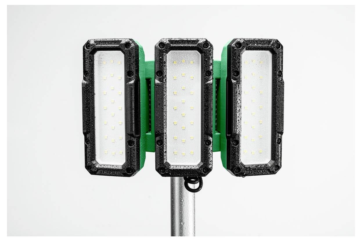 Három, fekete keretű és zöld hátoldalú téglalap alakú LED-reflektorból álló készlet, amely egy fémoszlophoz van rögzítve, sima fehér háttér előtt.