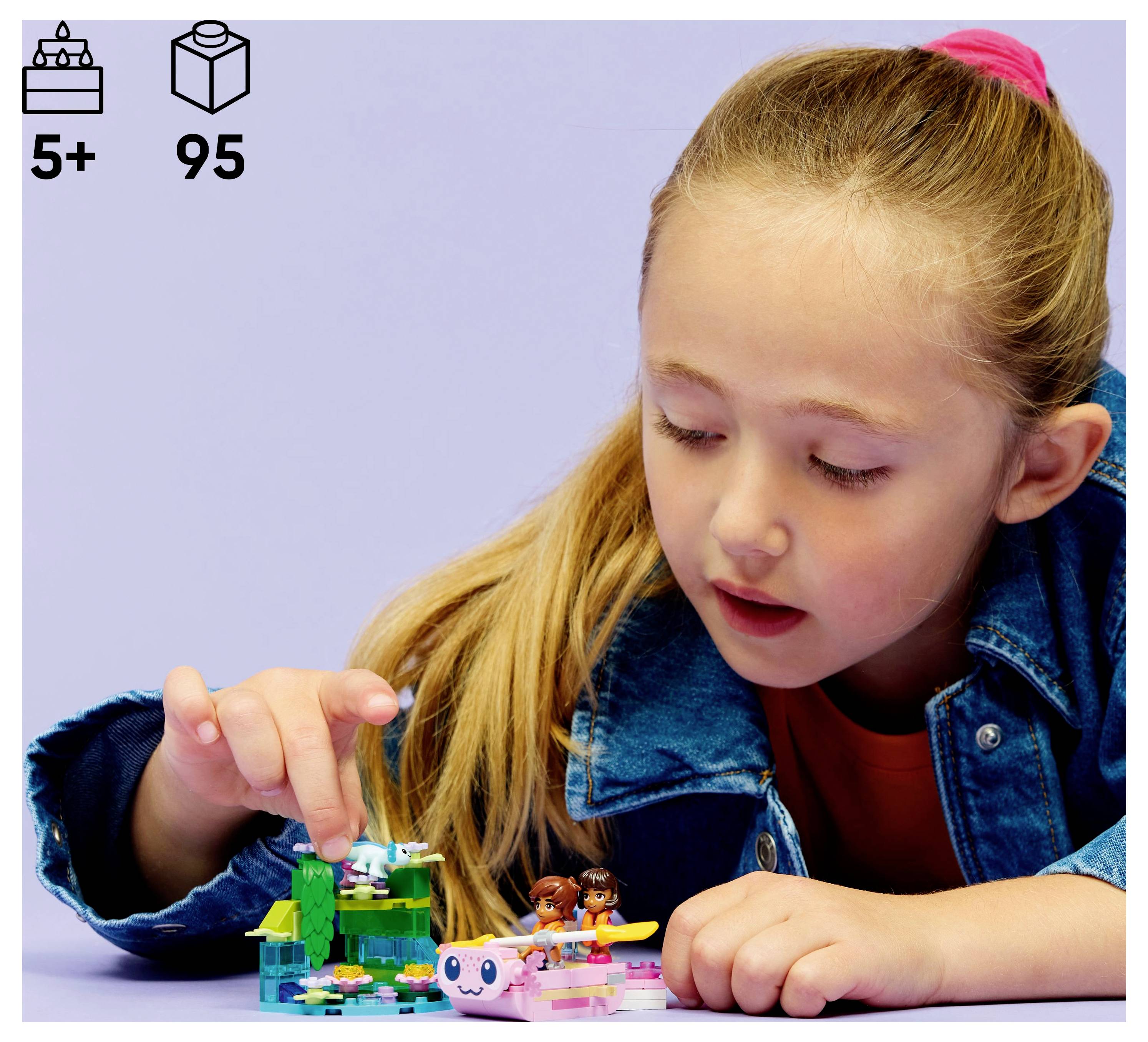 Egy gyerek egy kis, színes építőkészlettel játszik egy asztalon, amely egy modellt tartalmaz fákkal és figurákkal. A doboz 5 éves kor feletti ajánlást tartalmaz, és 95 darabból áll.