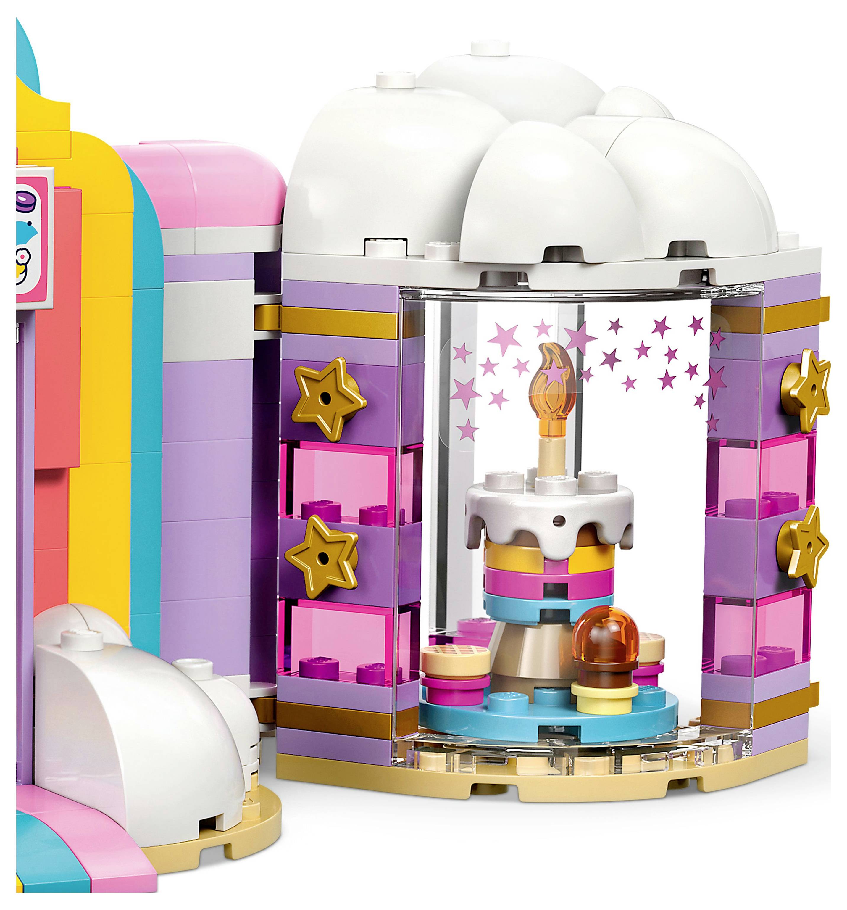 Egy játék épületszett, amely egy színes pékséget ábrázol kirakati ablakkal. Belül egy többszintes torta és egy muffin látható egy állványon.