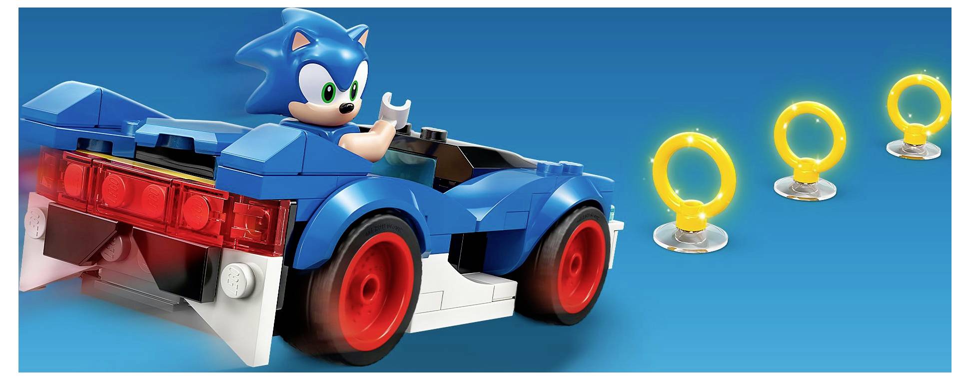 Egy kék játékautó kék sündisznó figurával és vörösen világító hátsó lámpákkal, három sárga gyűrűs játék mellett kék háttérben.