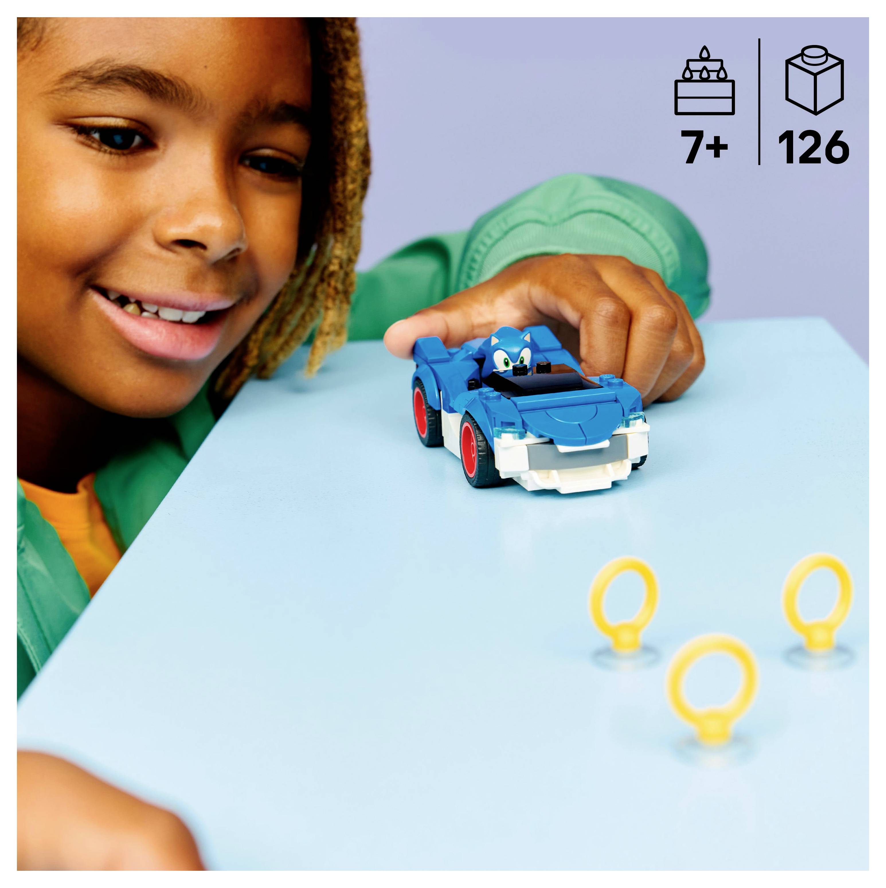 Egy kisgyerek egy kék játékautóval játszik, amelyen egy figura látható, körülötte kisméretű sárga gyűrűk vannak. A kép jelzi, hogy 7 éves kor felett ajánlott, és 126 darabból áll.