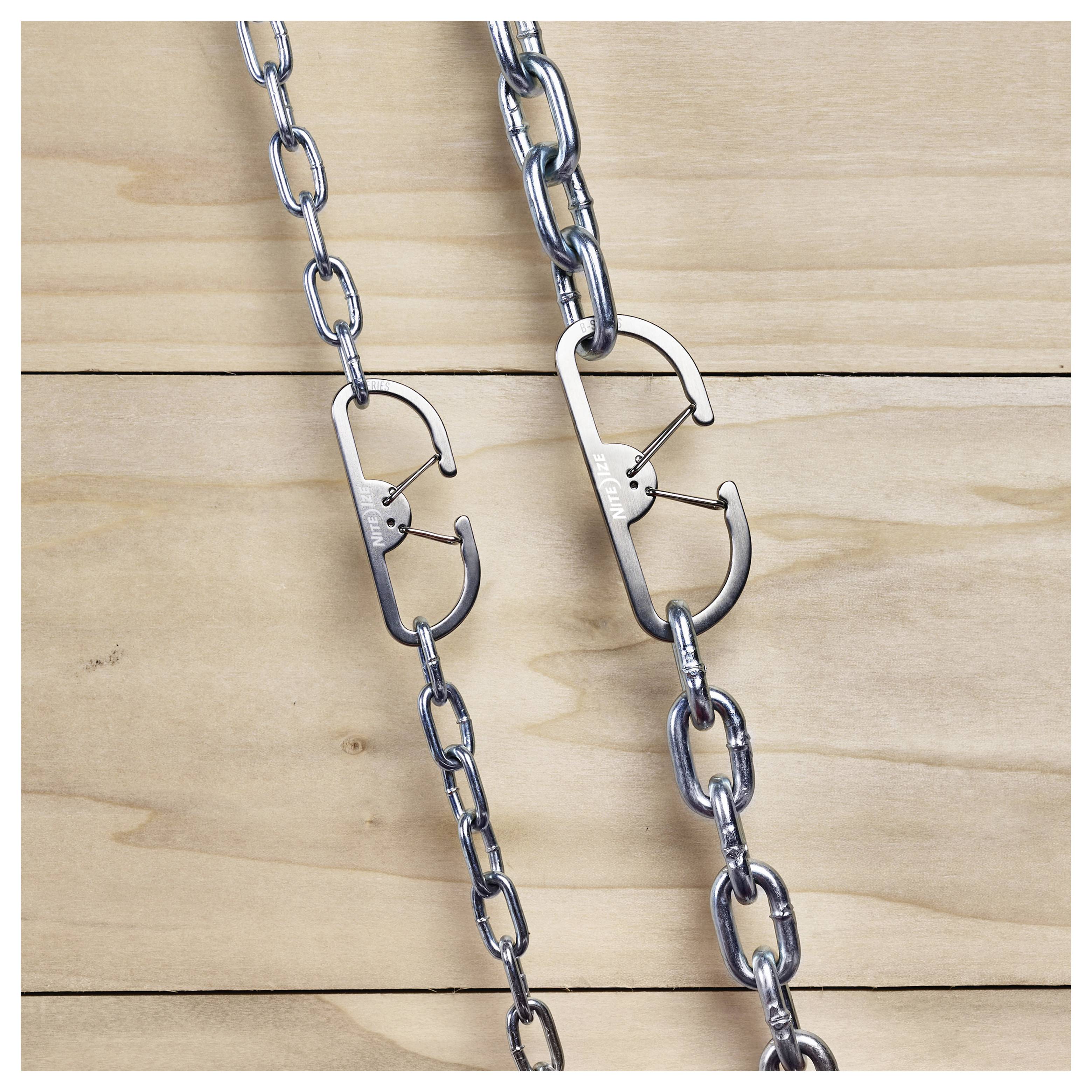 Karabinerekkel rögzített láncok egy fa felületen.